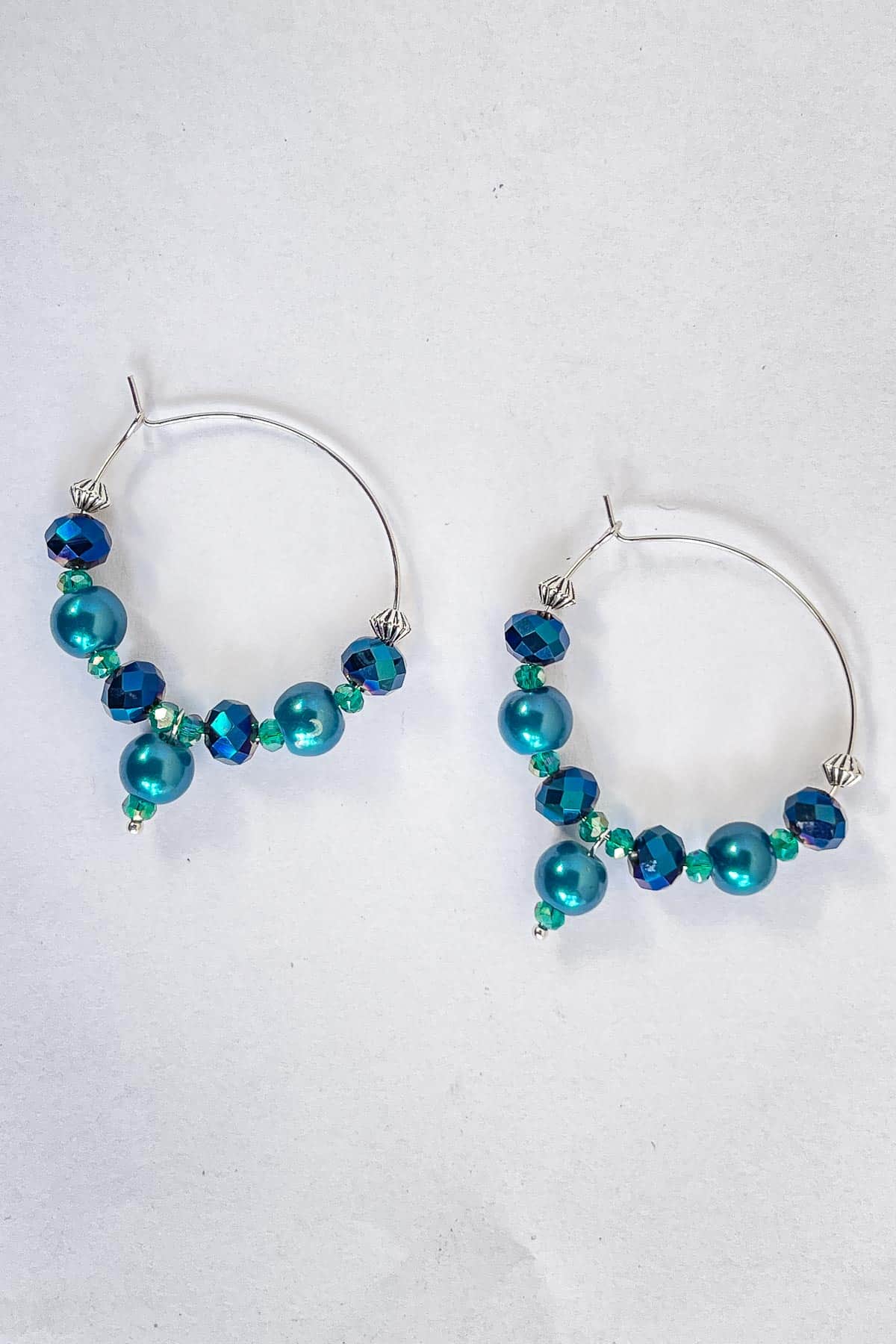 A pair of blue beaded hoop earrings in silver.