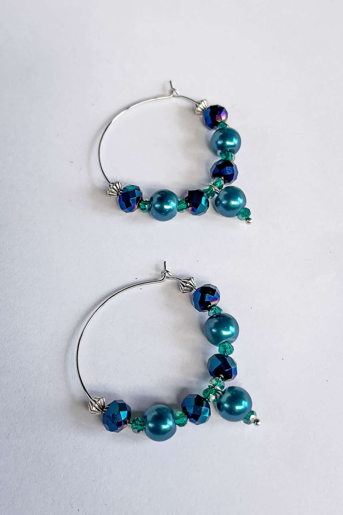 An elegant pair of beaded hoop earrings in blue crystal and pearl beads and silver metal hoops.