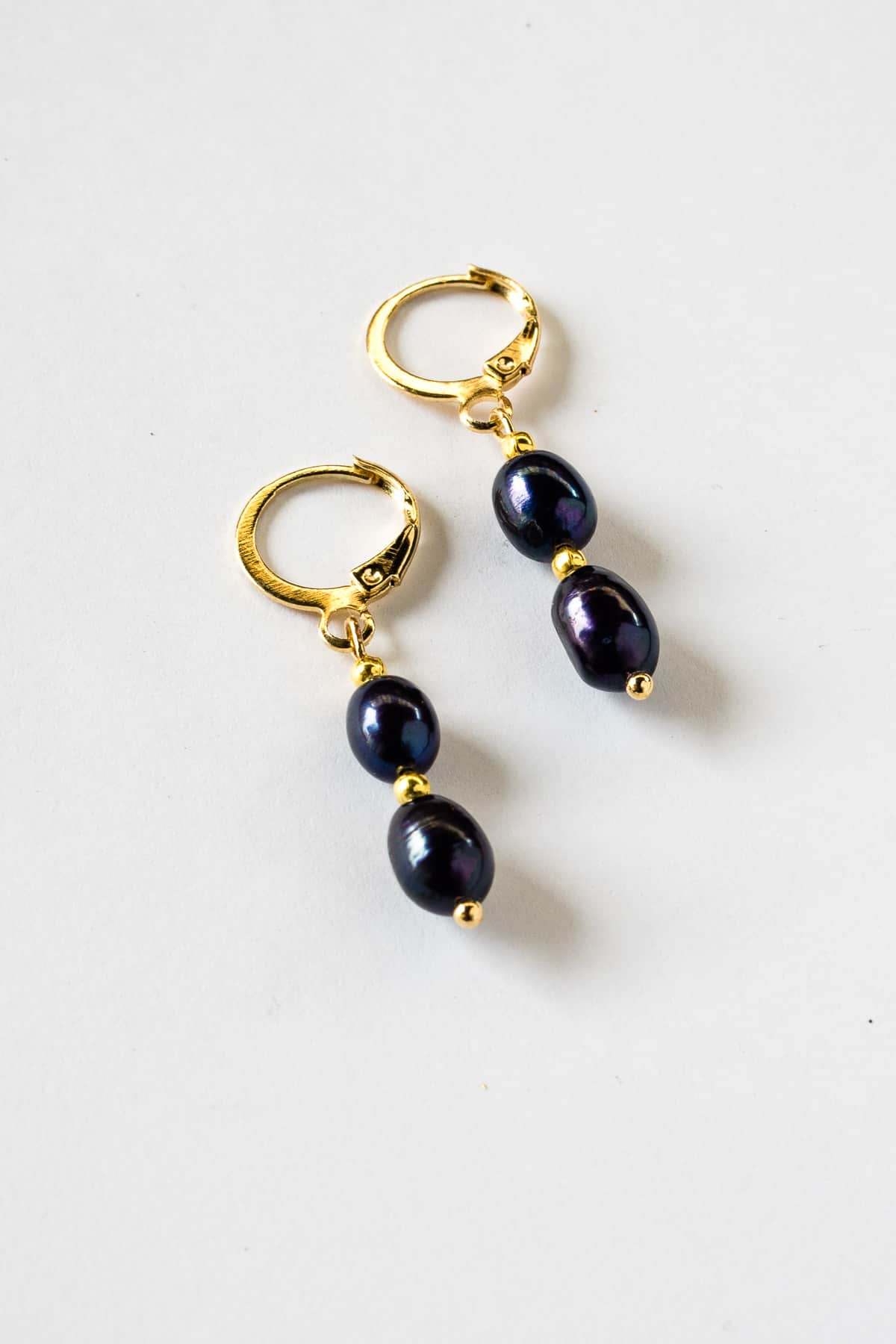 A pair of blue pearl earrings in gold lever back hoop.