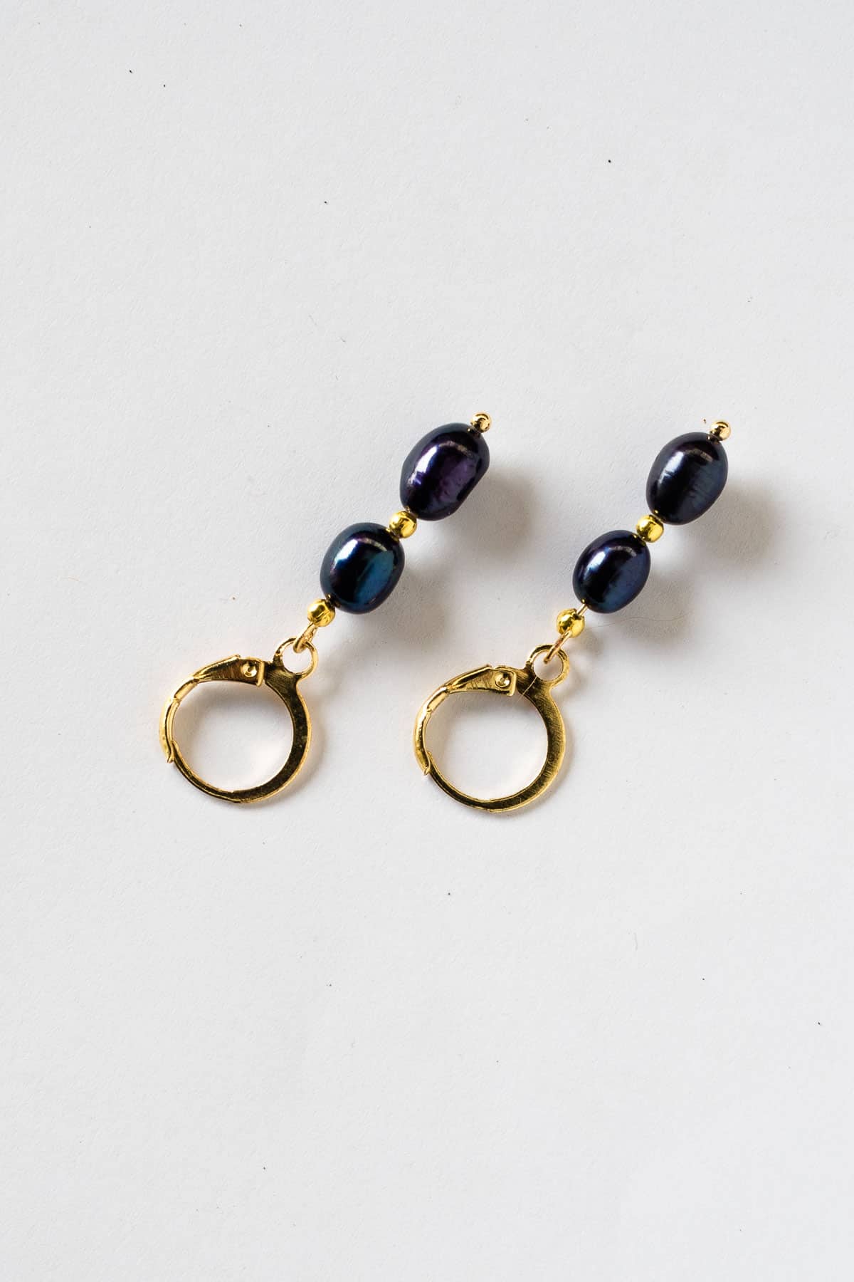 A pair of blue pearl earrings in gold lever back hoop.