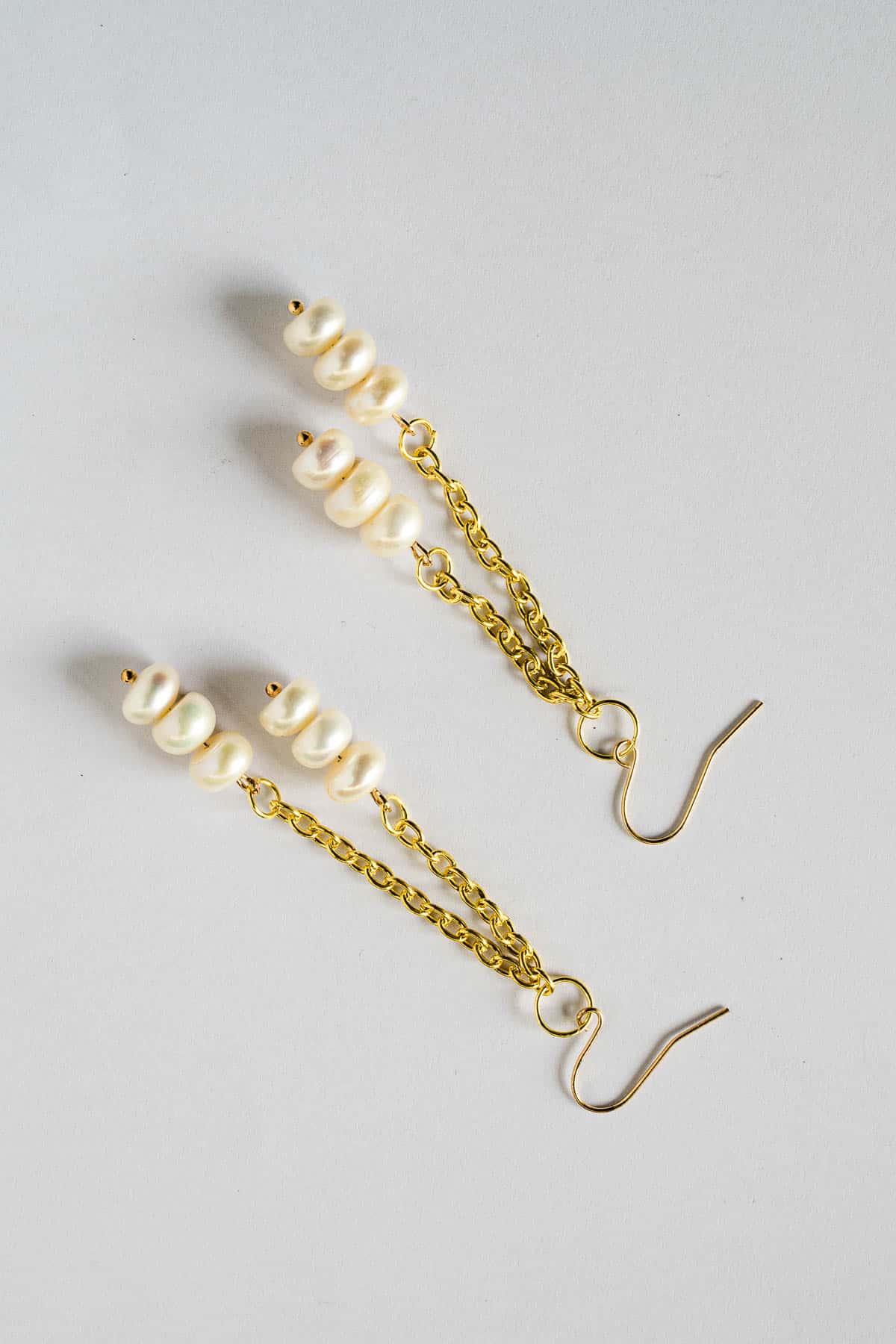 A pair of long white and gold freshwater pearl DIY dangle earrings.