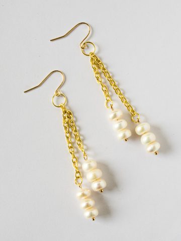 A pair of long white and gold freshwater pearl earrings.