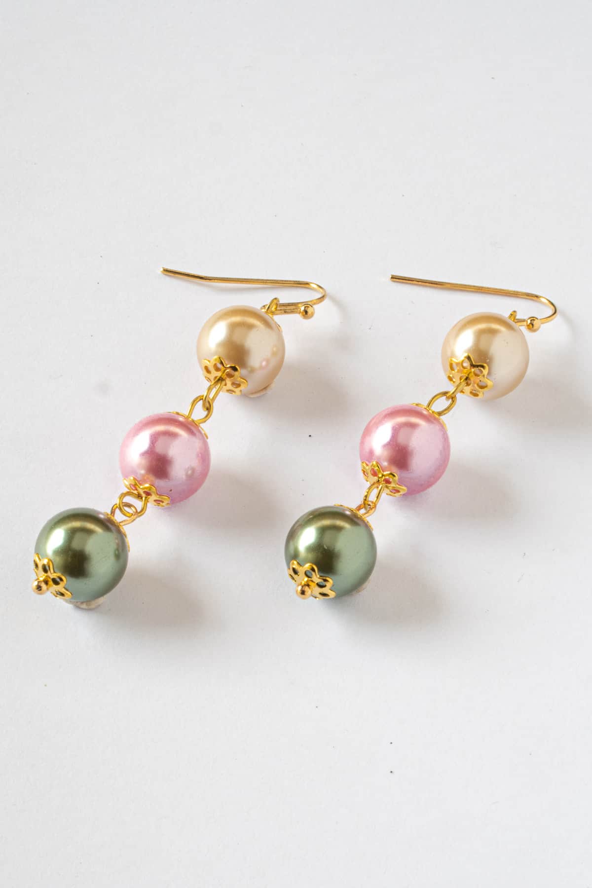 A pair of long earrings in green, pink and champagne.