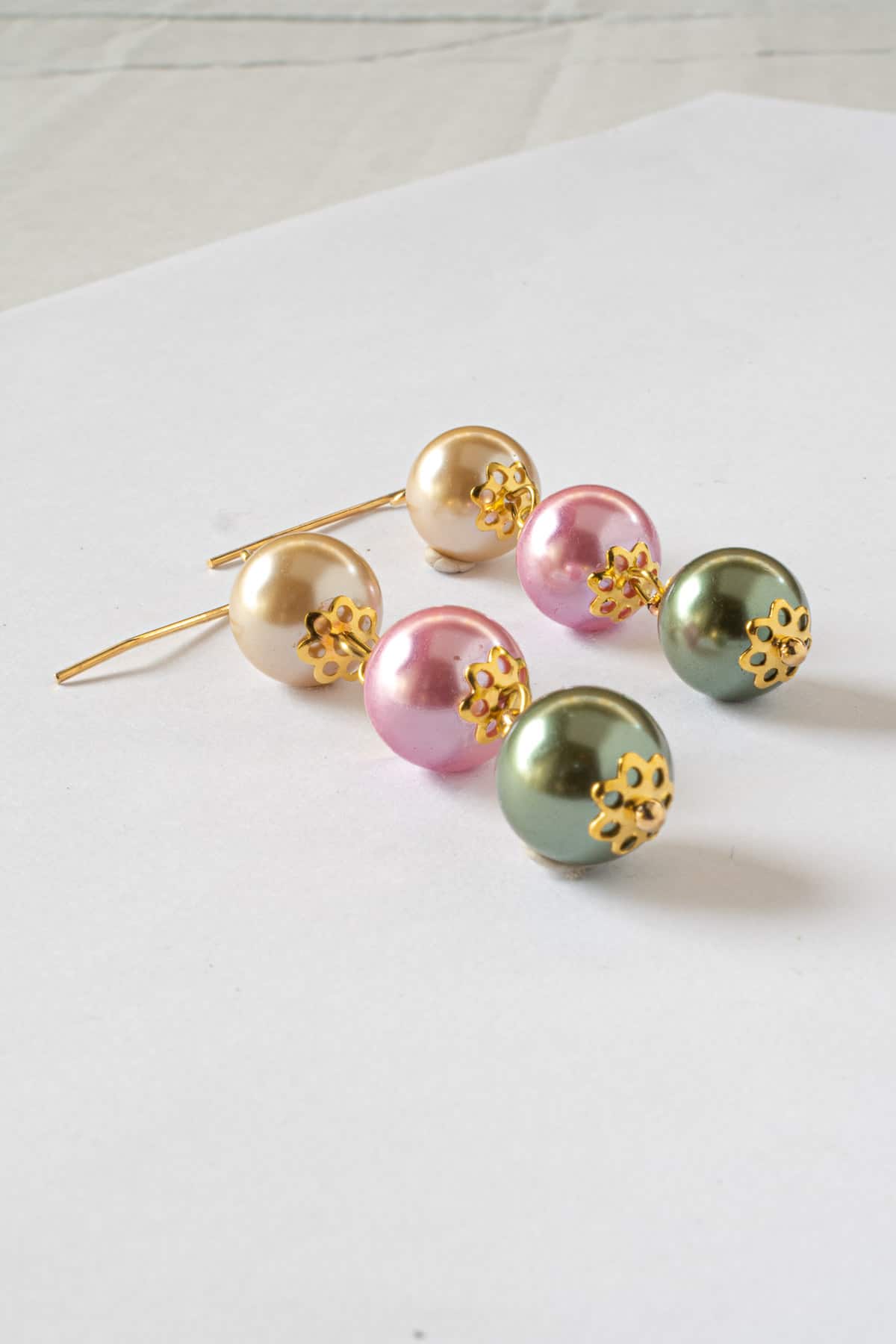 A pair of DIY pearl earrings in green, pink and champagne.