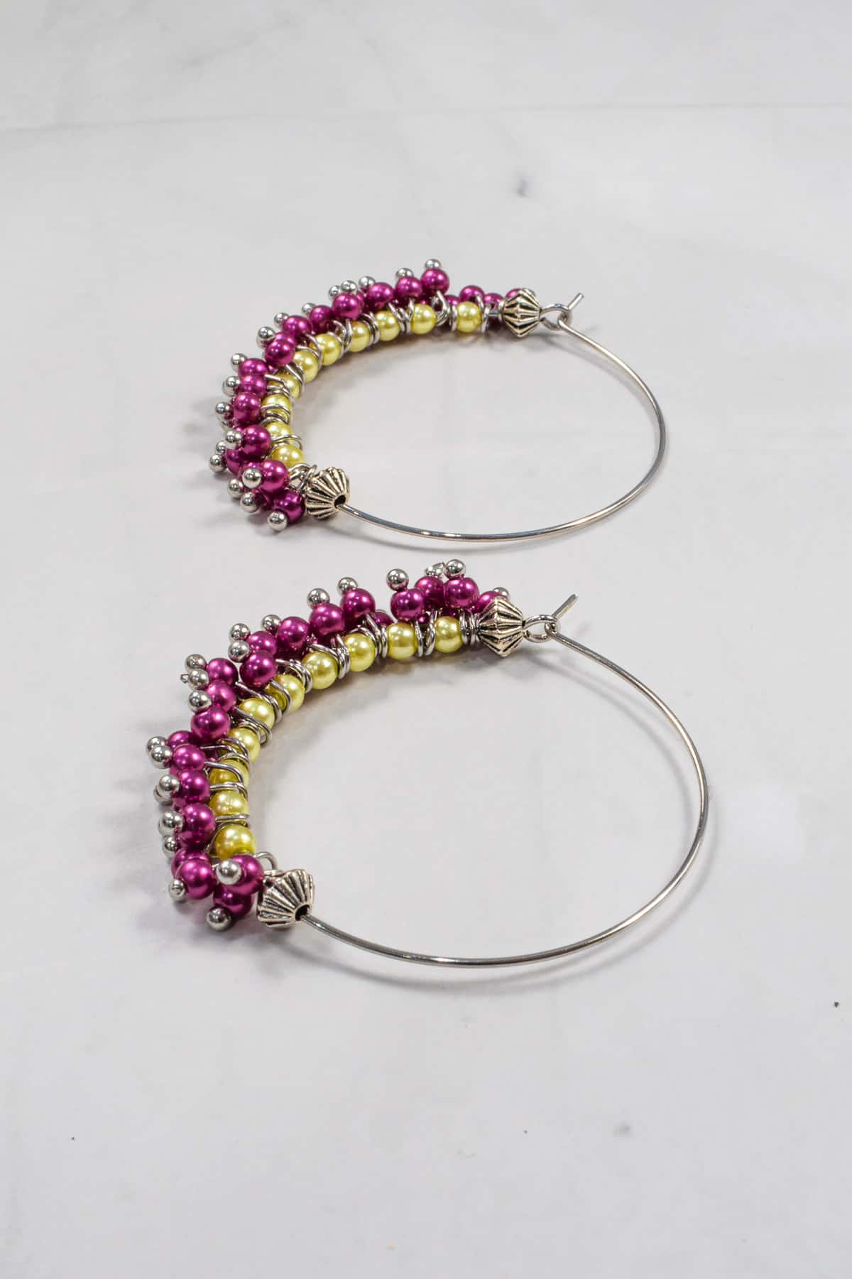 A pair of seed bead earrings in purple and green.
