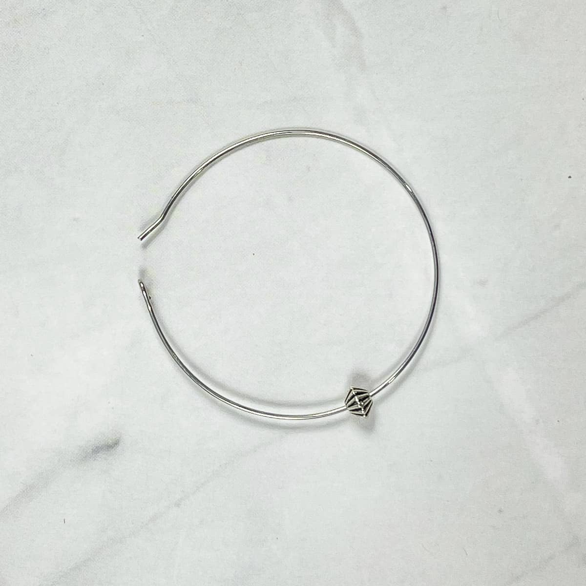 A silver bead in a hoop.
