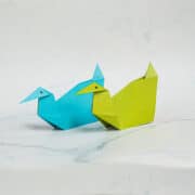 2 paper ducks against a marble background.