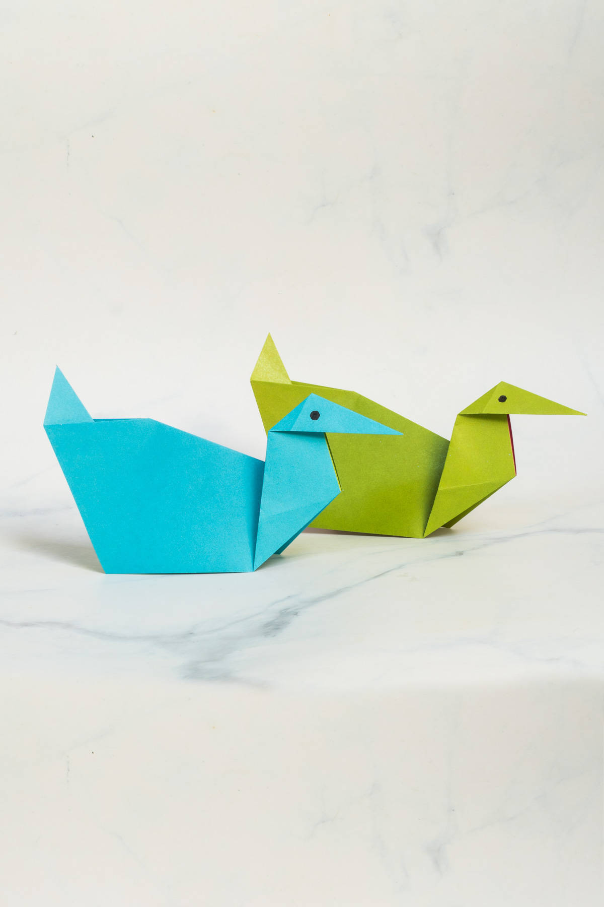 2 origami ducks against a marble background.