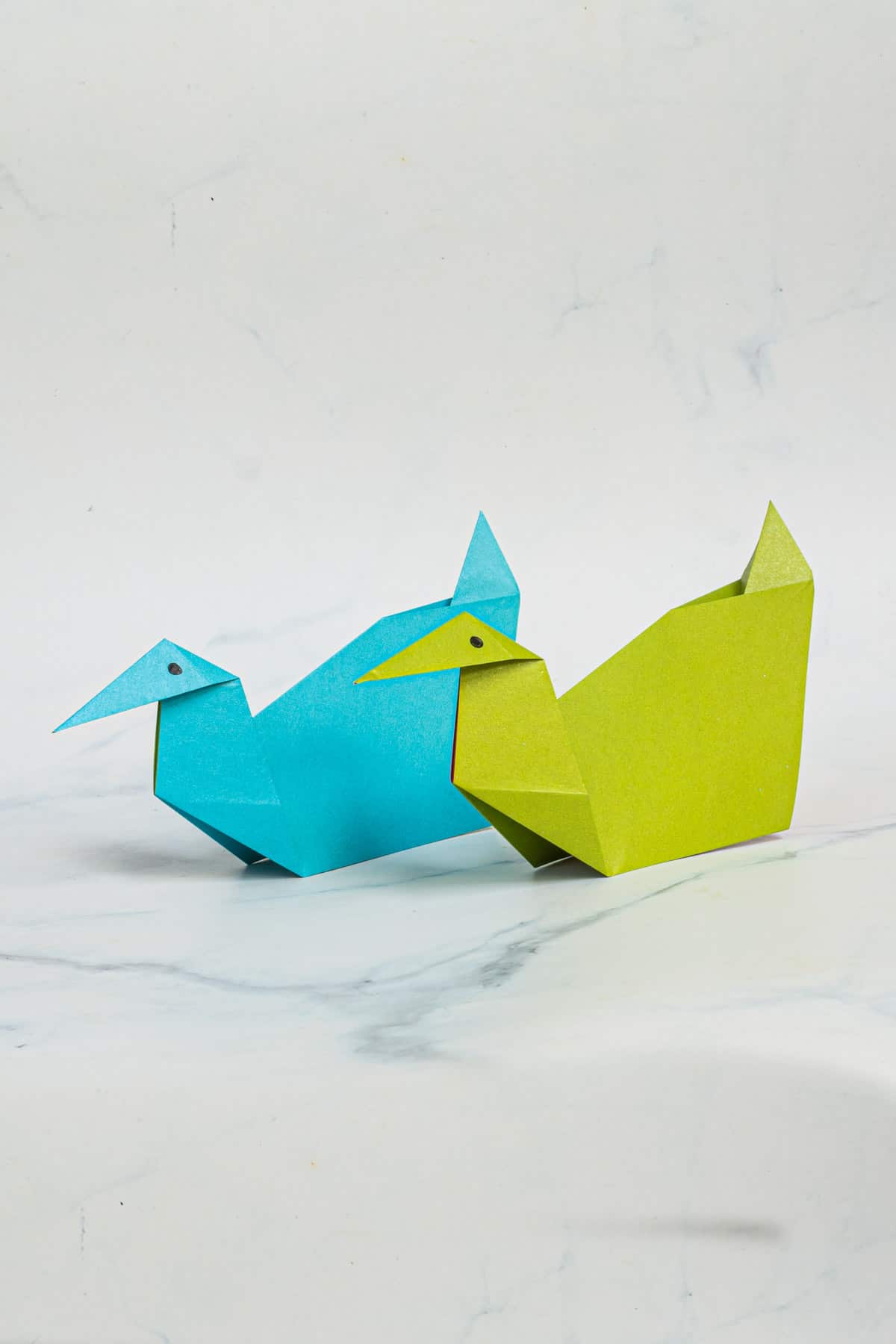 2 paper ducks against a marble background.