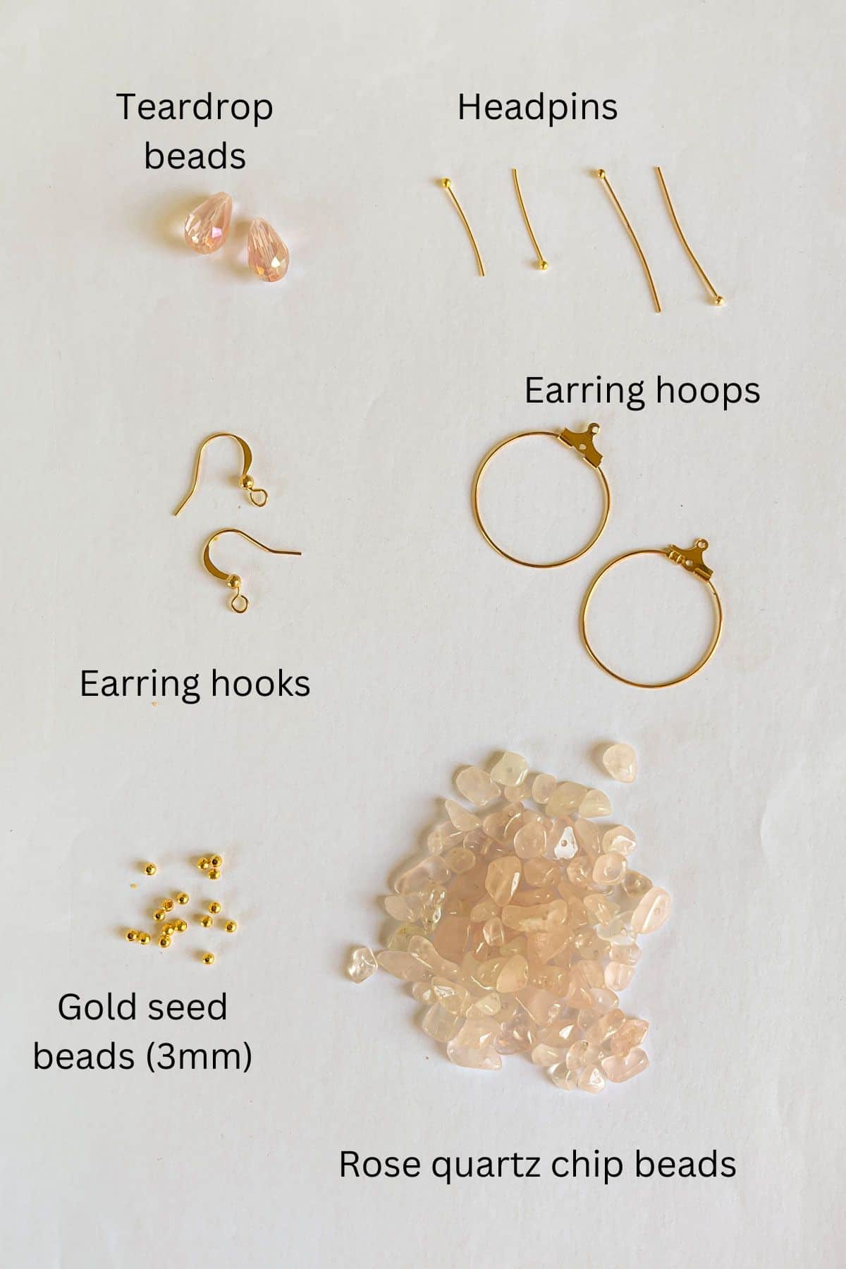 Teardrop beads, rose quartz chip beads, earring hooks, earring hoops, headpins and gold seed beads against a white background.