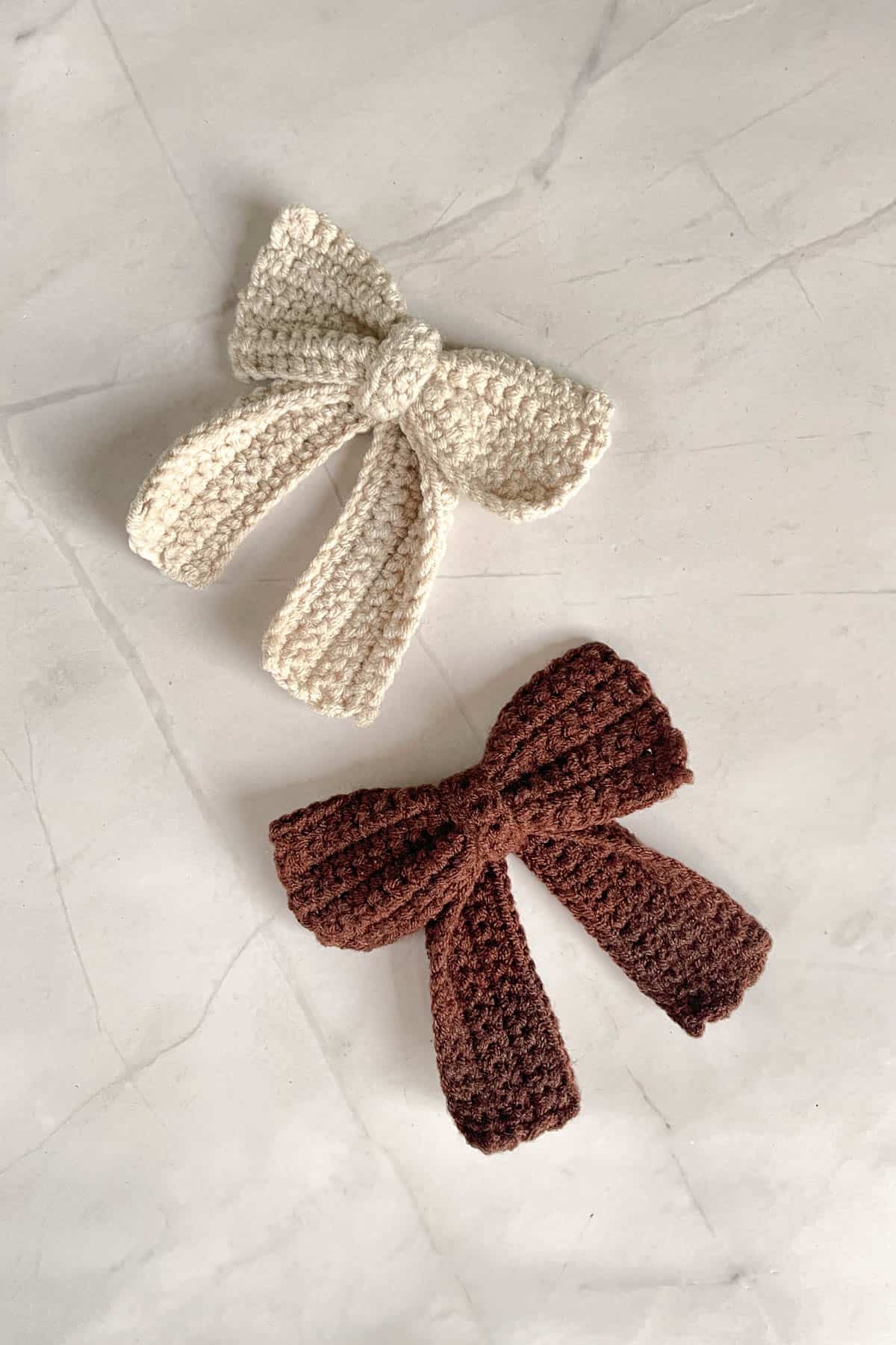 A brown and a beige crochet bow with tails.