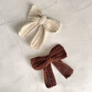 A brown and a beige crochet bow with tails.