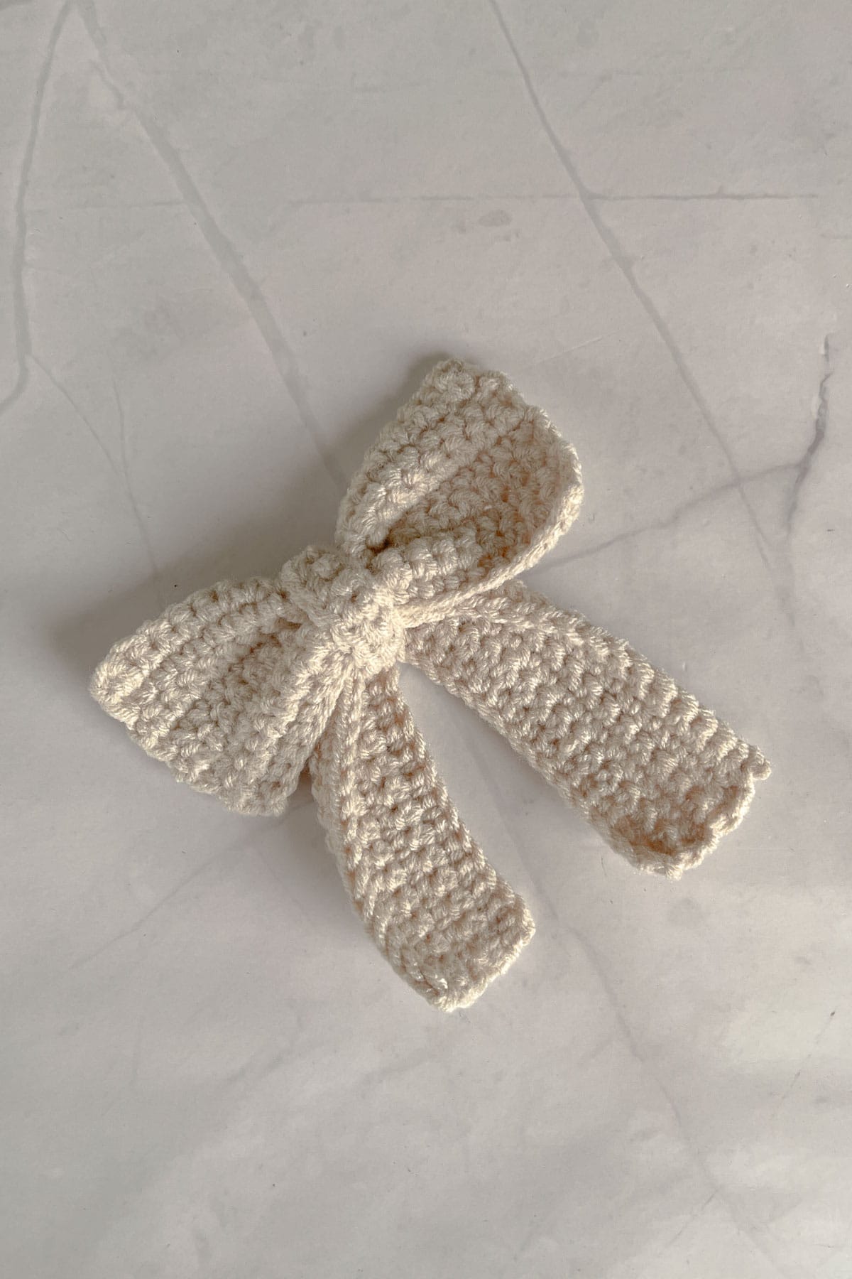 A beige crochet bow with tails.