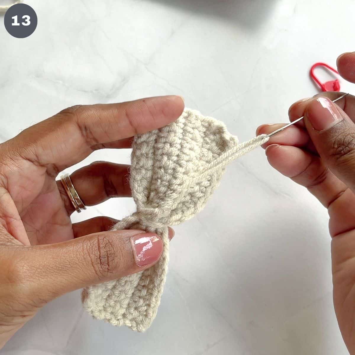 Threading excess yarn across stitches in a crochet bow.