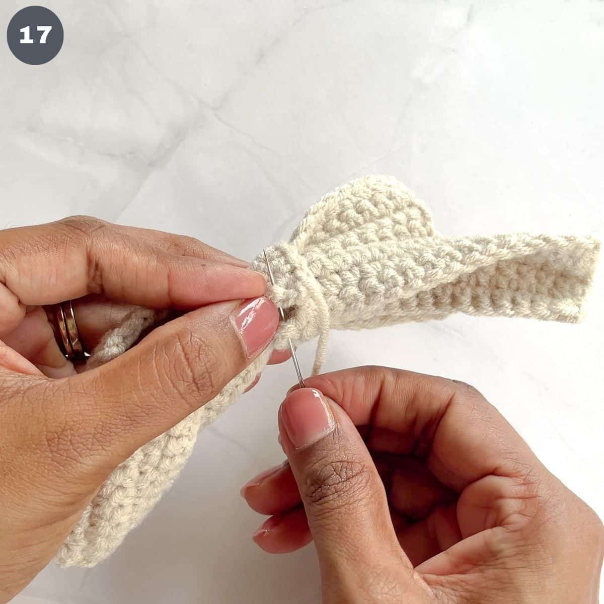 Stitching crochet tails to a crochet bow.
