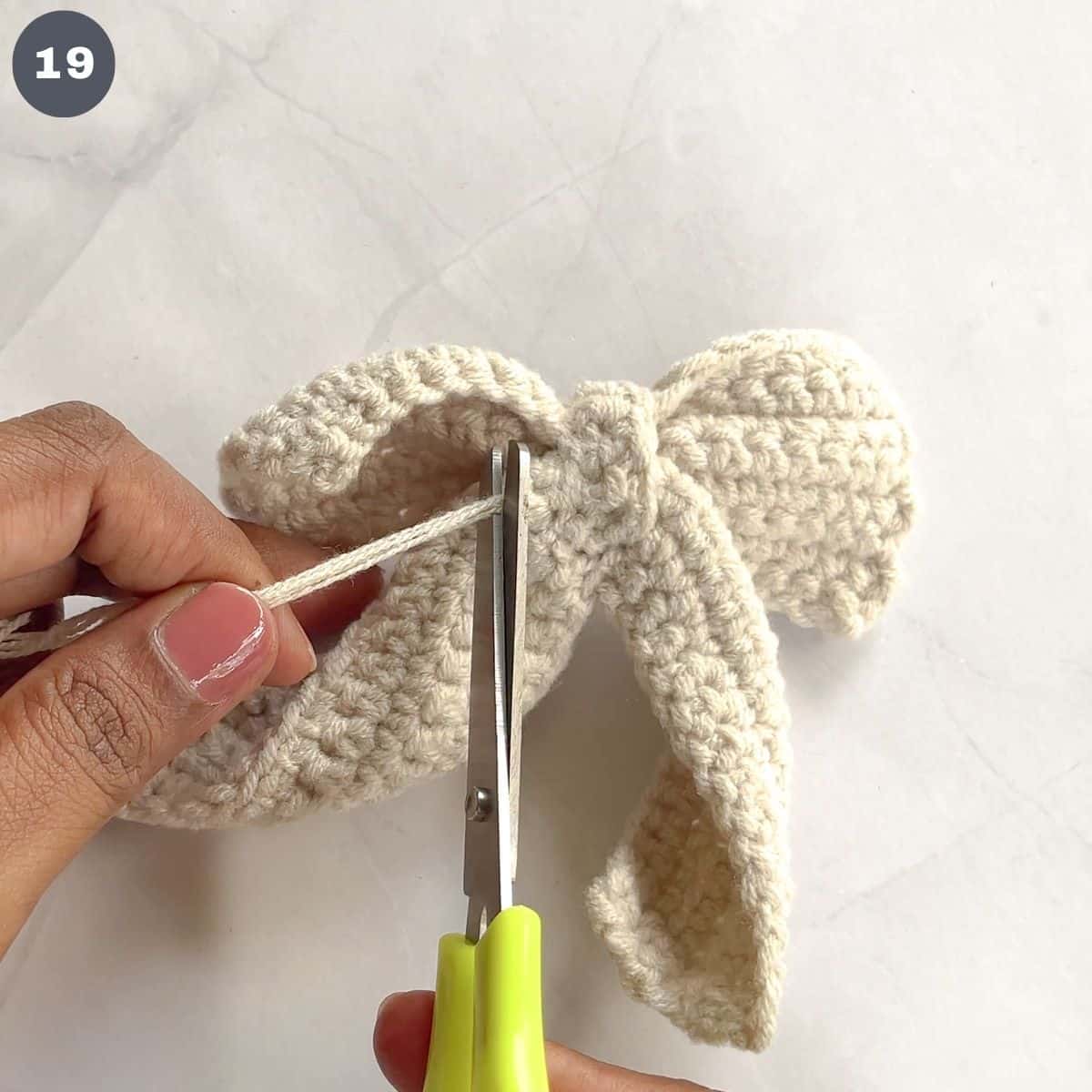 Cutting excess yarn off a crochet bow.