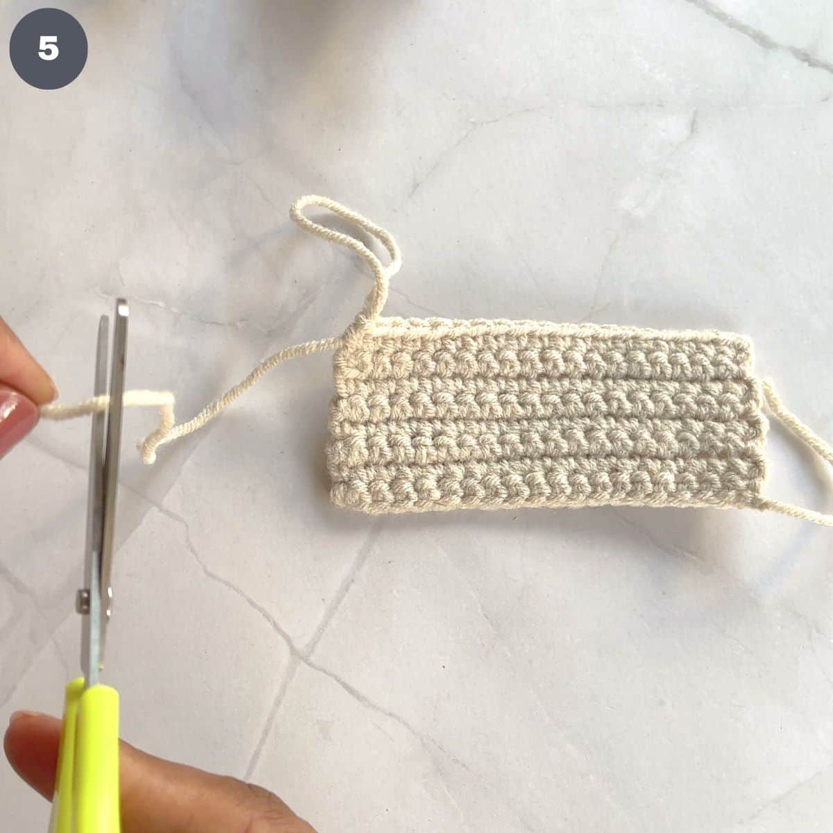 Cutting excess yarn with a pair of scissors.