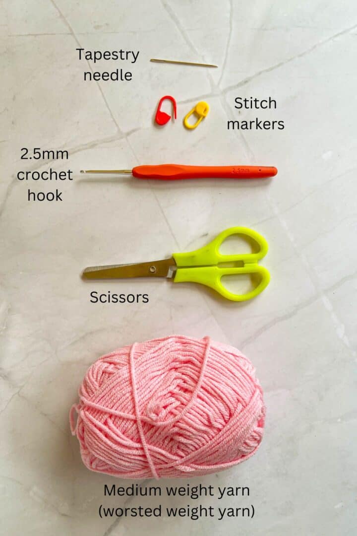 Pink yarn, green scissors, crochet hook, 2 stitch markers and a tapestry needle.