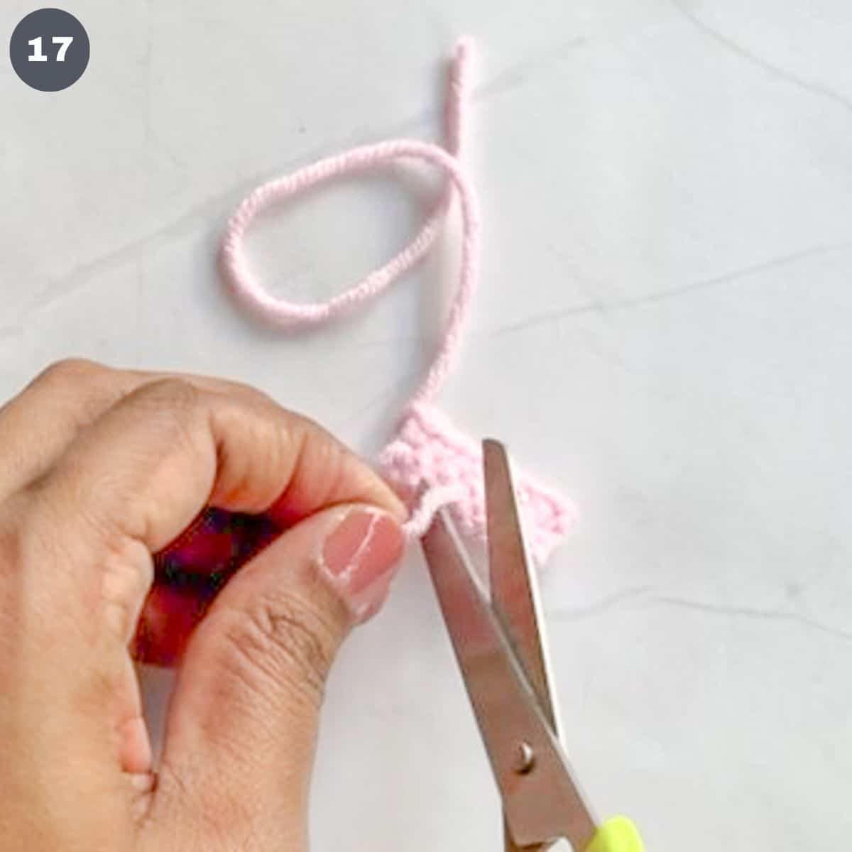 Cutting excess yarn with scissors.