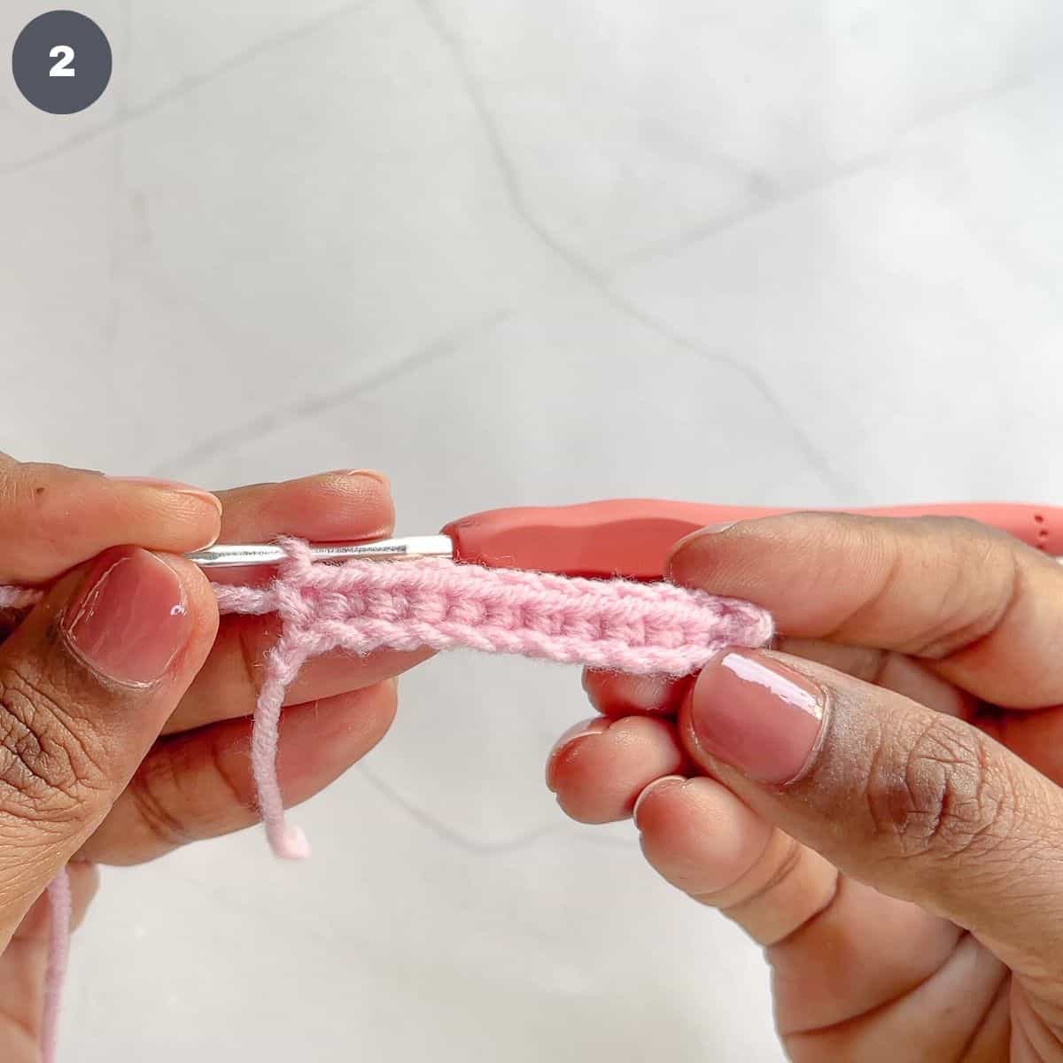 A row of single crochet stitches in pink yarn.