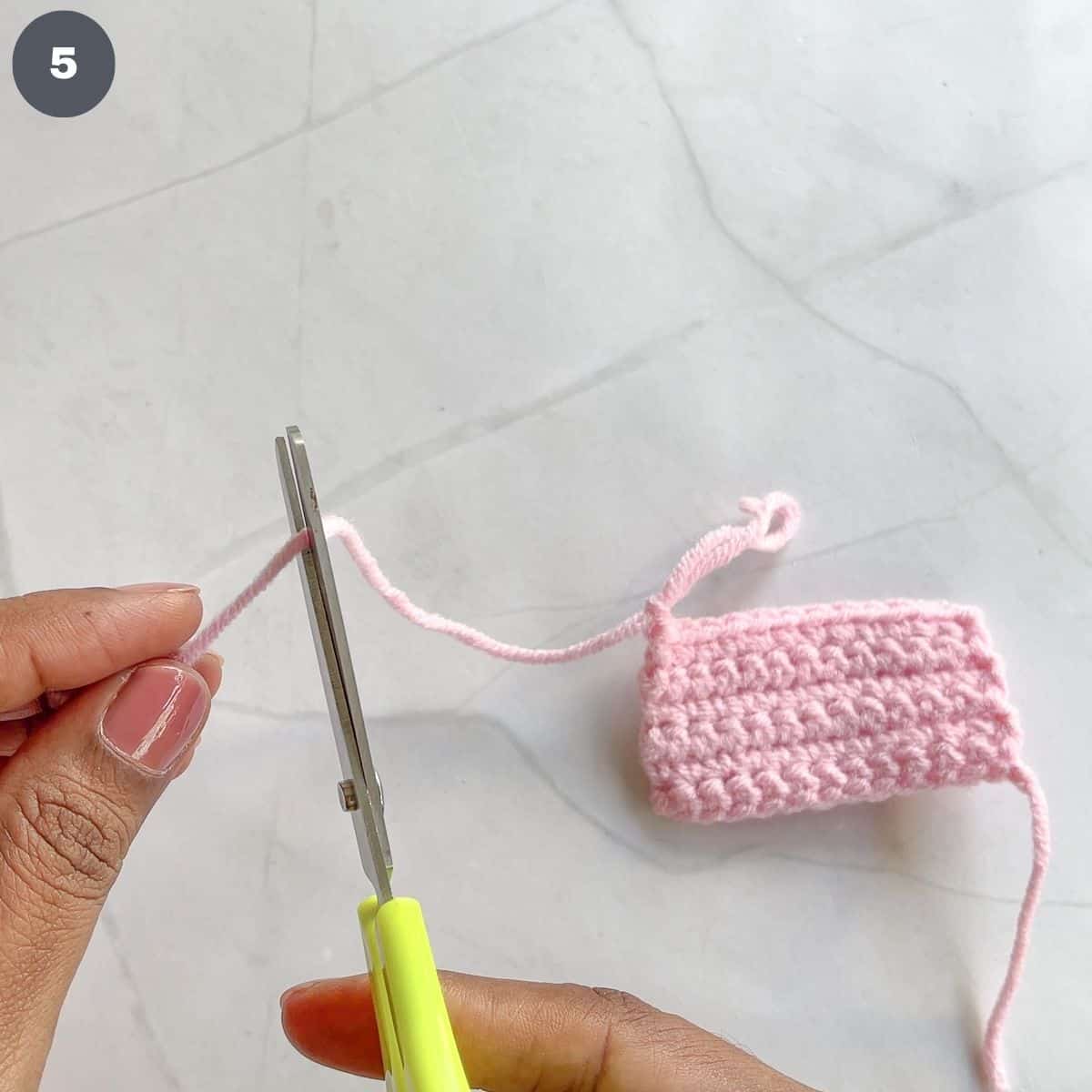 Cutting pink yarn with scissors.