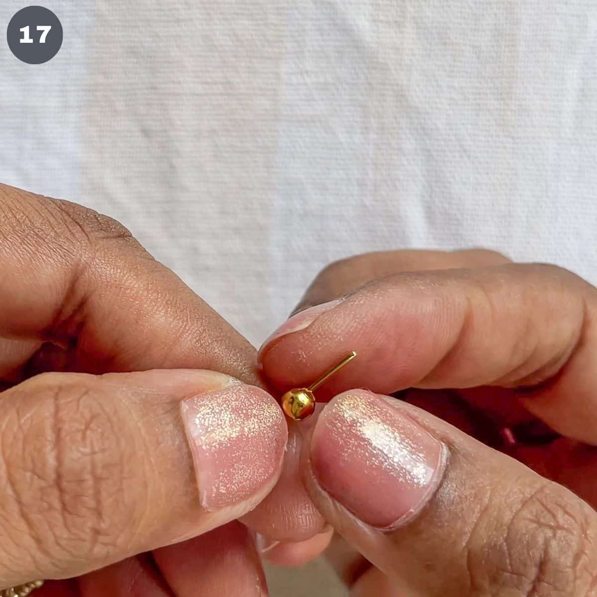 Inserting gold bead into an eye pin.