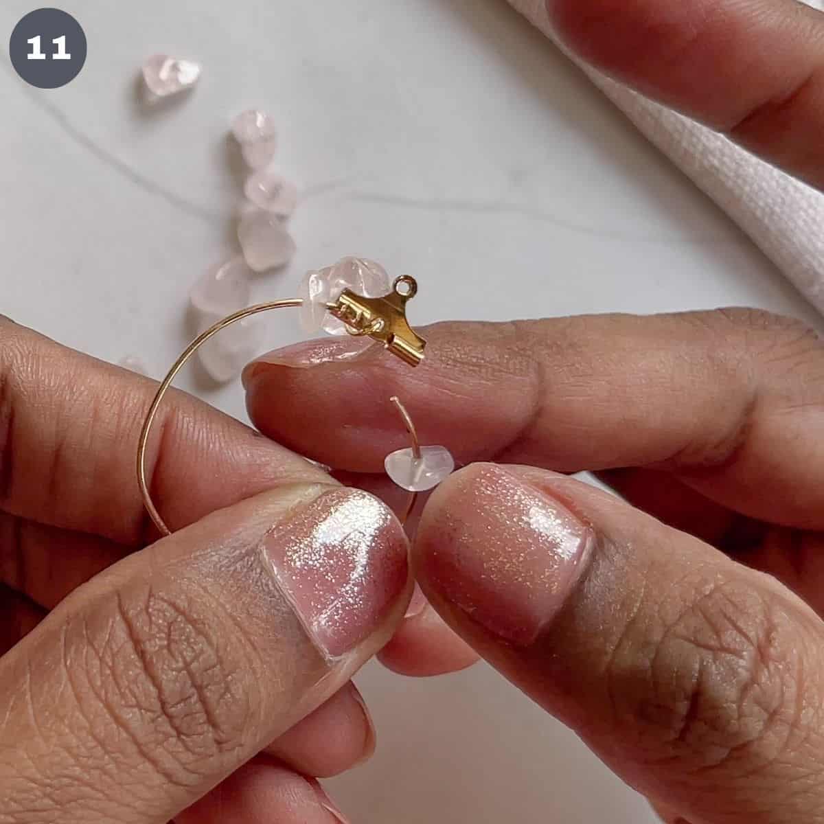 Inserting a rose quartz bead into a hoop.