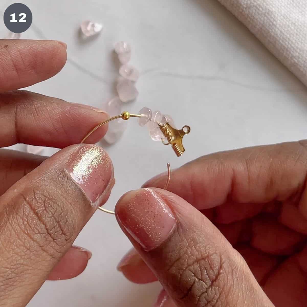 Inserting a gold bead into a hoop.