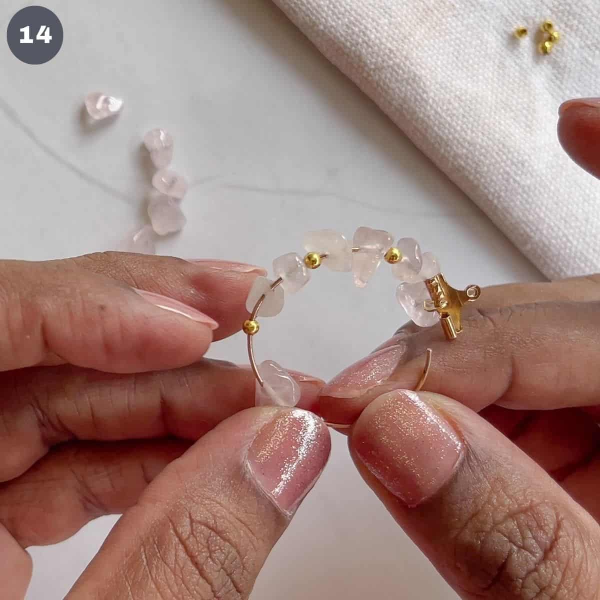 Inserting pink rose quartz beads into a hoop.