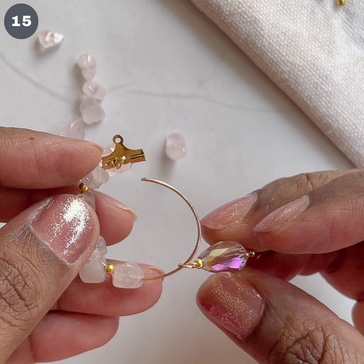 Inserting a pink dangle bead into a hoop.
