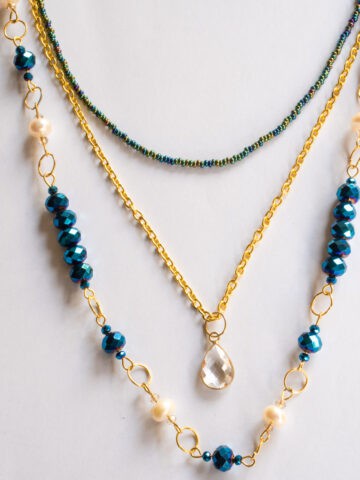 Seed bead strand, gold link chain with a pendant and a blue beads and pearls link chain in layers.