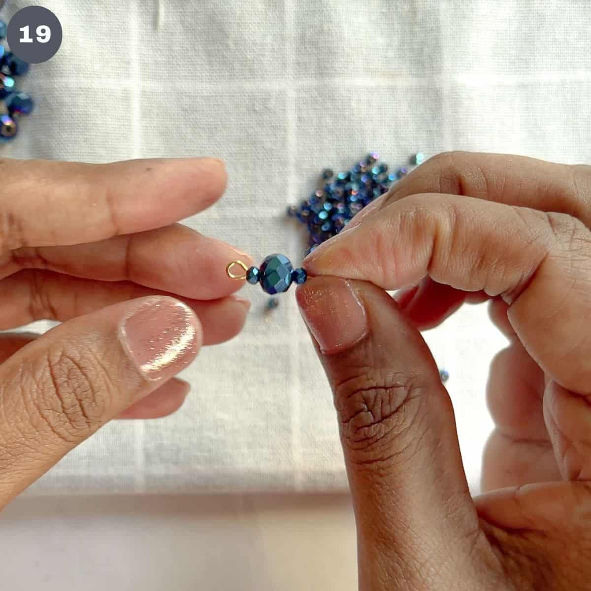 A row of small, big and small blue beads in an eye pin.